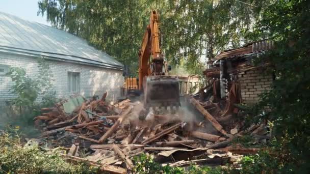 Byggnadsrivning. Hydrauliska grävmaskiner spadar skräp från rivna hus — Stockvideo