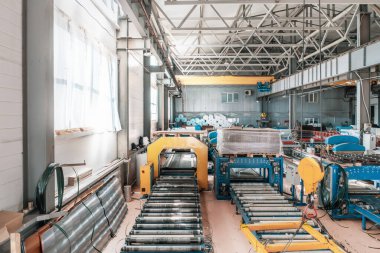 Metal çatı kiremitleri üretimi için endüstriyel fabrika atölyesi ya da deponun içi. Otomatik taşıma bantları ve hat ekipmanlarında çatı üretimi