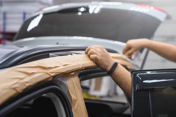 Worker in car service covering car with tape for work — Stock Photo, Image