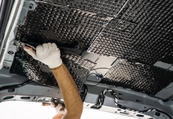 Pekerja tangan lem bahan kedap suara ke dalam atap mobil. Proses instalasi suara mobil — Stok Foto
