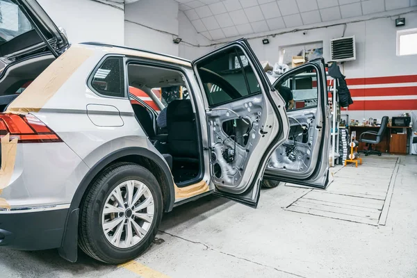 Coche en proceso de instalación de aislamiento acústico, puertas desmontadas sin revestimiento, garaje de reparación de automóviles en servicio —  Fotos de Stock