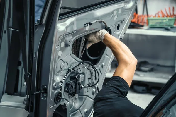 Pekerja jasa otomotif menutup pintu mobil untuk perbaikan, restorasi, penyetelan suara mobil atau memasang insulasi kebisingan atau kedap suara — Stok Foto