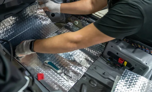 İşçi elleri ses geçirmez malzemeyi arabanın zeminine yapıştırıyor. Araba ses yalıtım kurulumu süreci — Stok fotoğraf