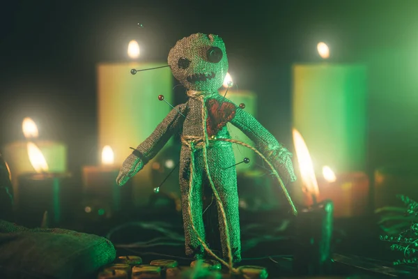 Voodoo Doll se zeleným dramatickým osvětlením ve tmě mezi svíčkami — Stock fotografie