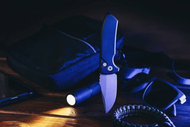 Modern mavi ışık altındaki insanlar için her gün taşıma ya da EDC hayatta kalma taktiği. Otomatik çakı, el feneri, paraşüt ve çanta.