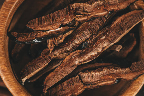 Sliced on pieces Ling Zhi Natural Chinese Herb or Reishi Mushroom, Ganoderma in wooden plate close up. Organic herbal medicine