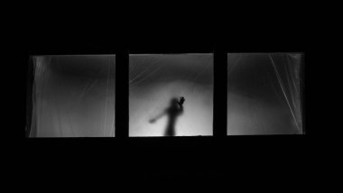 Sanat dekorasyonu. İçinde büyük pencereler ve zombiler olan eski bir ev. Penceredeki bulanık korkunç siluetler. Korku Cadılar Bayramı konsepti