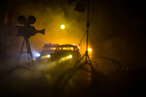 Action movie concept. Police cars and miniature movie set on dark toned background with fog. Police car chasing a car at night. Scene of crime accident. Selective focus