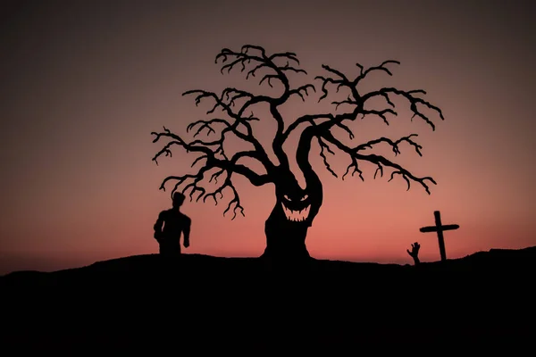 日落时分 墓地上的一些僵尸在走来走去 鬼脸可怕的万圣节树的轮廓 可怕的万圣节概念 有选择的重点 — 图库照片