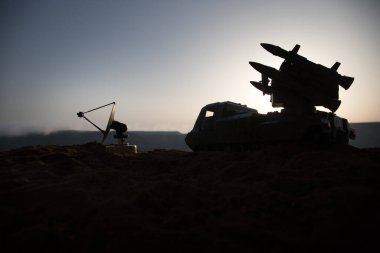 Yaratıcı sanat dekorasyonu. Gün batımında radar antenli mobil hava savunma aracı silueti. Roket fırlatıcı gökyüzüne nişan aldı ve saldırmaya hazır. Seçici odak