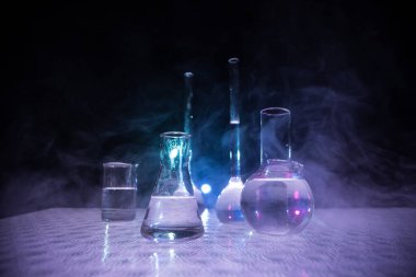 Eczane ve kimya teması. Araştırma laboratuarında çözeltisi olan cam deney şişesi. Bilim ve tıbbi geçmiş. Koyu renk arkaplan üzerinde laboratuvar test tüpleri, bilimsel araştırma ekipmanları konsepti