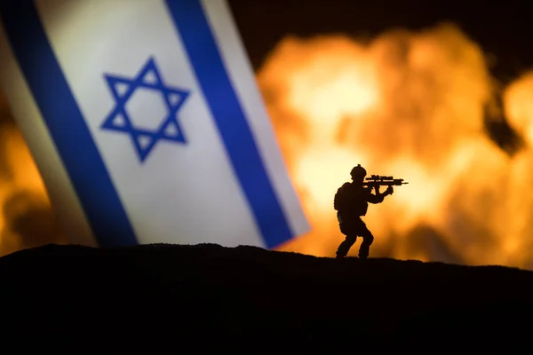 暗い背景に燃えるイスラエルの小さな旗 戦争の危機と国家間の政治的紛争の概念 イスラエルの旗に対する軍の戦闘シルエット 選択的焦点 — ストック写真