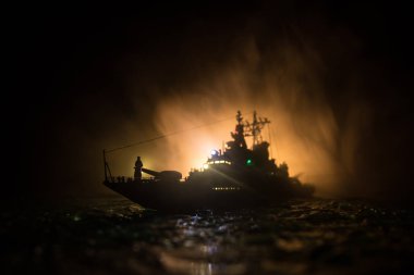 Savaş konsepti. Denizde gece savaşı sahnesi. Dramatik tonlu bulut etkisi. Gece savaş gemisinin silueti. Minyatür yaratıcı masa dekorasyonu. Seçici odak