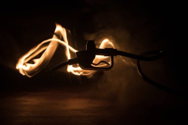 Yaratıcı bir kavram. Koyu tonlu sisli arka planda benzin tabancası minyatürü. Yakıt tabancası yanıyor. Seçici odak