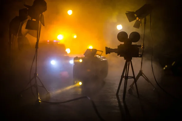 Action movie concept. Police cars and miniature movie set on dark toned background with fog. Police car chasing a car at night. Scene of crime accident. Selective focus