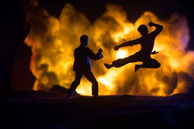 Yanan Orman 'da karate sporcuları gece dövüşü sahnesi. Karakter karatesi. Sanatçı figürü dekorasyonu. Spor konsepti. Işıkla süslenmiş sisli bir arka plan. Seçici odak