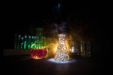 Eczane ve kimya teması. Araştırma laboratuarında çözeltisi olan cam deney şişesi. Bilim ve tıbbi geçmiş. Koyu renk arkaplan üzerinde laboratuvar test tüpleri, bilimsel araştırma ekipmanları konsepti