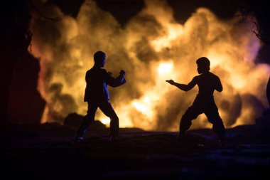 Yanan Orman 'da karate sporcuları gece dövüşü sahnesi. Karakter karatesi. Sanatçı figürü dekorasyonu. Spor konsepti. Işıkla süslenmiş sisli bir arka plan. Seçici odak