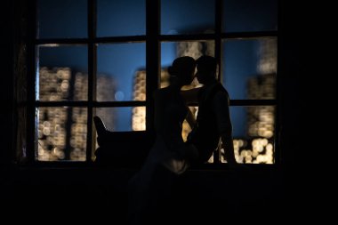 Dollhouse 'un penceresinden gece minyatür bir şehrin güzel manzarası. Pencerede romantik bir çift. El yapımı gerçekçi bebek eviyle sanat masası dekorasyonu. Seçici odak.