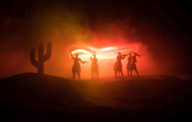 Batı konsepti. Geceleri kovboylar arası savaş. Ölümüne düello. Seçici odak noktasında rengarenk sisli arkaplan üzerine yaratıcı sanat dekorasyonu