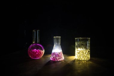 Eczane ve kimya teması. Araştırma laboratuarında çözeltisi olan cam deney şişesi. Bilim ve tıbbi geçmiş. Koyu renk arkaplan üzerinde laboratuvar test tüpleri, bilimsel araştırma ekipmanları konsepti
