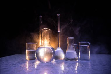 Eczane ve kimya teması. Araştırma laboratuarında çözeltisi olan cam deney şişesi. Bilim ve tıbbi geçmiş. Koyu renk arkaplan üzerinde laboratuvar test tüpleri, bilimsel araştırma ekipmanları konsepti