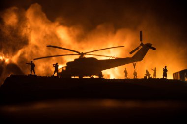 Askeri helikopterin silueti çatışma bölgesinden uçmaya hazır. Çölden başlayan sisli arka ışıklandırmalı helikopterle dekore edilmiş gece görüntüleri. Seçici odaklanma. Savaş konsepti