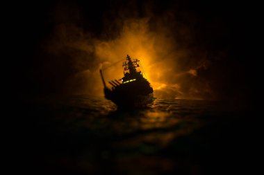 Savaş konsepti. Denizde gece savaşı sahnesi. Dramatik tonlu bulut etkisi. Gece savaş gemisinin silueti. Minyatür yaratıcı masa dekorasyonu. Seçici odak