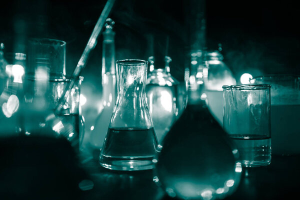 Pharmacy and chemistry theme. Test glass flask with solution in research laboratory. Science and medical background. Laboratory test tubes on dark toned background , science research equipment concept