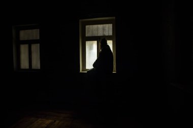 Rusya ve Ukrayna arasındaki savaşın kavramsal fotoğrafı. Geceleri vitrindeki asker silueti. Pencereli eski ürkütücü oda. Dışarıdaki patlama..