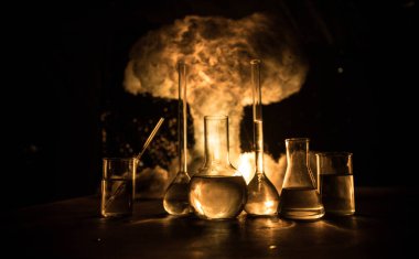Eczane ve kimya teması. Araştırma laboratuarında çözeltisi olan cam deney şişesi. Bilim ve tıbbi geçmiş. Soyut patlama bulutu arkaplanındaki laboratuvar test tüpleri. Seçici odak