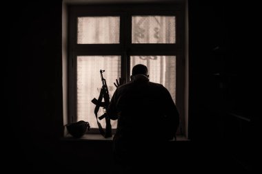 Rusya ve Ukrayna arasındaki savaşın kavramsal fotoğrafı. Geceleri vitrindeki asker silueti. Pencereli eski ürkütücü oda. Dışarıdaki patlama..