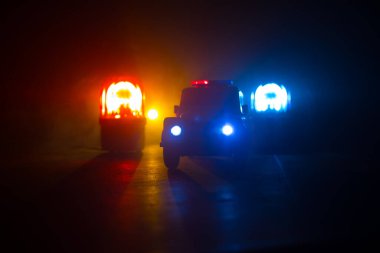 Polis arabası sisli bir arabayı gece takip ediyor. 911 acil durum arabası suç mahalline doğru hızla gidiyor. Yaratıcı dekorasyon. Seçici odak