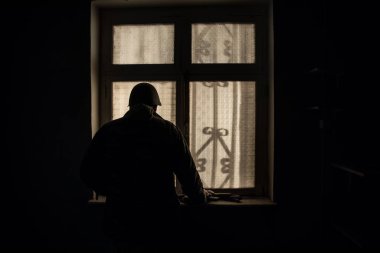 Rusya ve Ukrayna arasındaki savaşın kavramsal fotoğrafı. Geceleri vitrindeki asker silueti. Pencereli eski ürkütücü oda. Dışarıdaki patlama..