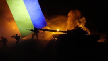 Rus savaşı Ukrayna konseptinde. Ukrayna bayrağına karşı silahlı askerlerin silueti ve yanmış şehir. Yaratıcı sanat dekorasyonu. Gece dövüşü sahnesi. Seçici odak