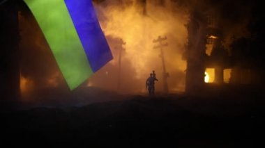 Silüet asker, küçük çocuğu ateşten omuzunda taşıyor. Rus savaşı Ukrayna konseptinde. Yanmış şehirden küçük bir çocukla taşınan adam savaşta yok oldu. Seçici odak