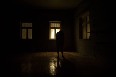 Geceleri penceresi olan terk edilmiş ürkütücü odada korku silueti. Korku sahnesi. Cadılar Bayramı konsepti.