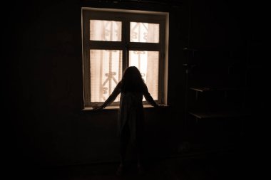 Geceleri penceresi olan terk edilmiş ürkütücü odada korku silueti. Korku sahnesi. Cadılar Bayramı konsepti.