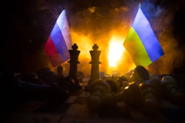 Rusya ve Ukrayna arasındaki savaş, satranç tahtası, askerler ve patlamanın arka planındaki ulusal bayrakları kullanarak savaşın kavramsal görüntüsü. Ukrayna ve Rusya krizi. Seçici odak