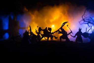 Süvari ve piyadelerle ortaçağ savaş sahnesi. Şekillerin siluetleri ayrı nesneler olarak, karanlık tonlu sisli arka planda ortaçağ şatosuyla savaşan savaşçılar arasında. Seçici odak