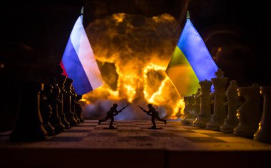 War between Russia and Ukraine, conceptual image of war using chess board, soldiers and national flags on the background of explosion. Ukrainian and Russian crisis. Selective focus