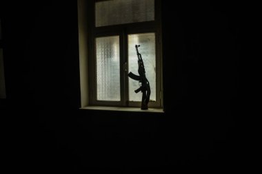 Rusya ve Ukrayna arasındaki savaşın kavramsal fotoğrafı. Rus silahı (tüfek) gece pencere eşiğinde. Pencereli eski ürkütücü oda. Dışarıdaki patlama..