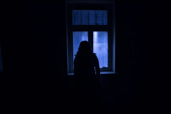 Horror silhouette inside abandoned creepy room with window at night. Horror scene. Halloween concept.
