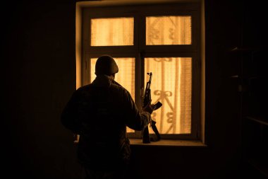 Rusya ve Ukrayna arasındaki savaşın kavramsal fotoğrafı. Geceleri vitrindeki asker silueti. Pencereli eski ürkütücü oda. Dışarıdaki patlama..