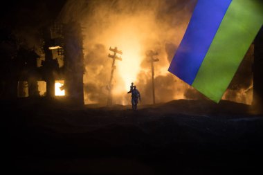Silüet asker, küçük çocuğu ateşten omuzunda taşıyor. Rus savaşı Ukrayna konseptinde. Yanmış şehirden küçük bir çocukla taşınan adam savaşta yok oldu. Seçici odak