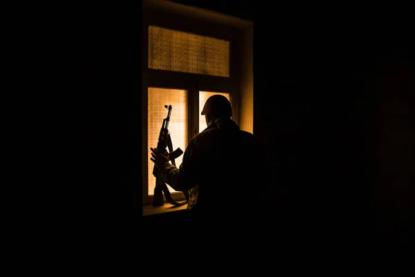Conceptual photo of war between Russia and Ukraine. Silhouette of soldier at window at night. Old creepy room with window. Explosion outside.