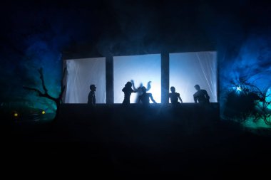 Sanat dekorasyonu. İçinde büyük pencereler ve zombiler olan eski bir ev. Penceredeki bulanık korkunç siluetler. Korku Cadılar Bayramı konsepti