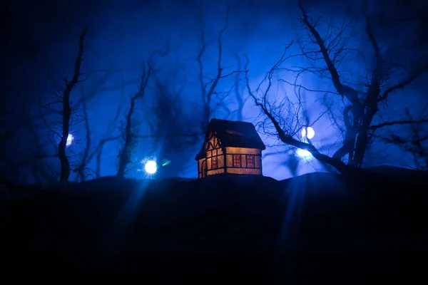 Old house with a Ghost in the forest at night or Abandoned Haunted Horror House in fog. Old mystic building in dead tree forest. Horror Halloween concept.