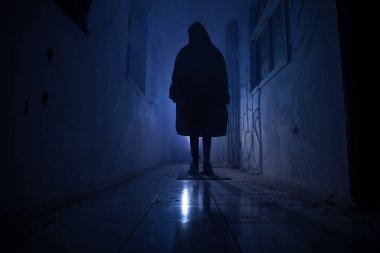 Cadılar Bayramı konsepti Karanlık koridorda balkabağı kafalı ürkütücü bir siluet. Arka planda sis olan tonlu bir ışık. Seçici odaklanma. Uzun deklanşör.