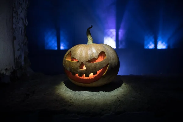 Scary Halloween pumpkin in the mystical house window at night or halloween pumpkin in night on abandoned room with window. Selective focus